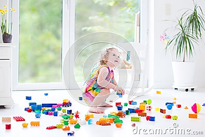 Curly laughing toddler girl playing with colorful blocks Stock Photo