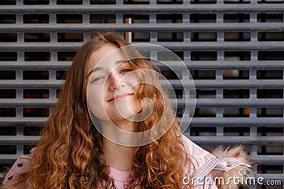 Curly redheaded girl looks at the camera with a funny expression on her face, pulling up her chin a little bit. Stock Photo