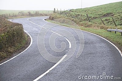 Curved country empty rural road white lines and hedge Stock Photo