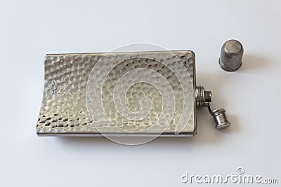 Curved metal flask lying on its side, cap off and top open, drinking alcoholism addiction concept Stock Photo