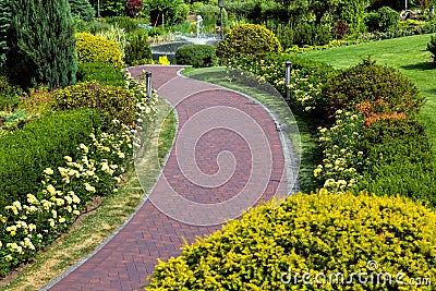 A curved path of paving slabs in a park area with landscape design. Stock Photo