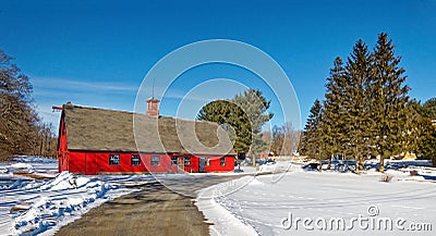 Curved road leading to red barn in Winter snow Stock Photo