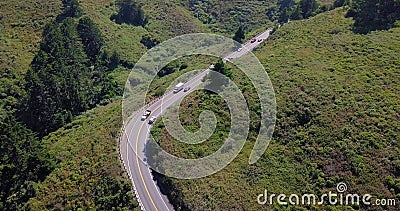 Curved road surrounded by forest green trees cars