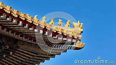 Curved roofs in traditional Chinese style with figures on the blue sky background. The Imperial Palace in Beijing Stock Photo