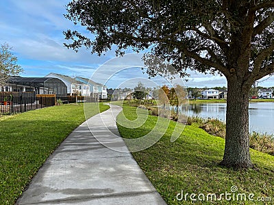 A curved sidewalk near a lake that is a walking path behind homes in an Orlando neighborhood Editorial Stock Photo