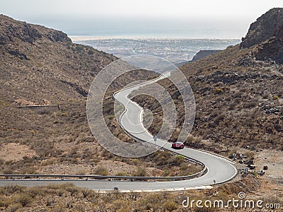 Curved winding road with a red car in the mountains in Gran Canaria Stock Photo