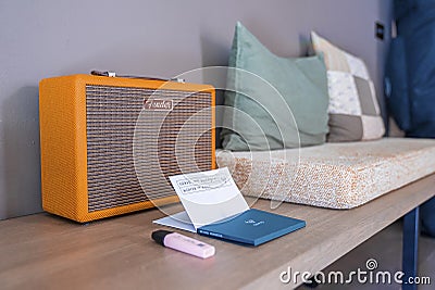 Cushions with antique radio and notepad on wooden table against wall Editorial Stock Photo