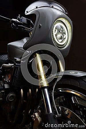 Custom caferacer motorbike on dark background with its headlight on. Stock Photo