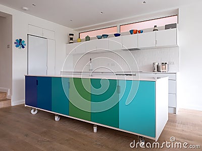 Custom designed kitchen island in open plan kitchen on industrial castor wheels, retro design painted in blue and green colours. Stock Photo