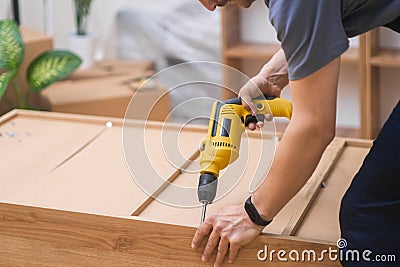 Custom furniture assembling handyman fixing fasteners on cabinet back with professional screwdriver Stock Photo