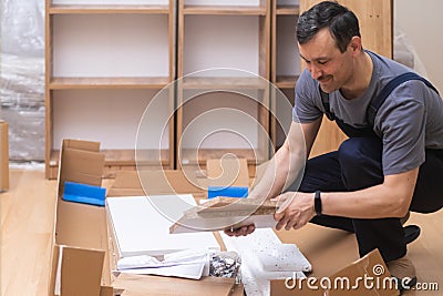 Custom furniture production and assembly master in overalls putting wooden planks to wall Stock Photo