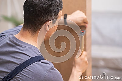 Custom furniture production focused worker hammering nail into wardrobe made of wood Stock Photo