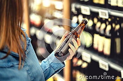 Customer buying beer in liquor store. Lager, craft or wheat beer. IPA or pale ale. Woman at alcohol shelf. Stock Photo