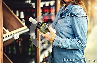 Customer buying white wine or sparkling drink. Alcohol aisle in store or supermarket. Woman holding bottle. Stock Photo