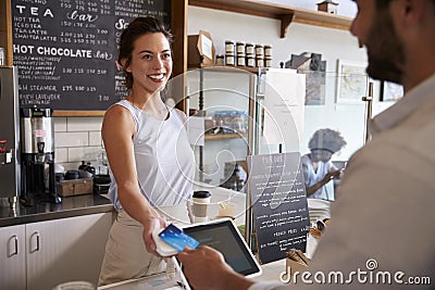 Customer at coffee shop pays smiling waitress with card Stock Photo