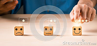 For customer evaluation and satisfaction with goods and service, a wooden block with an emotion face and yellow stars is used Stock Photo