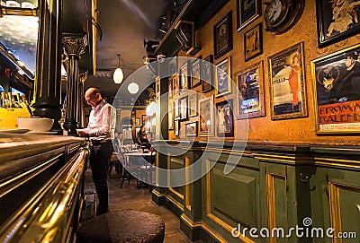 Customer making an order at bar counter, small restaurant with vintage interior, old paintings and posters Editorial Stock Photo