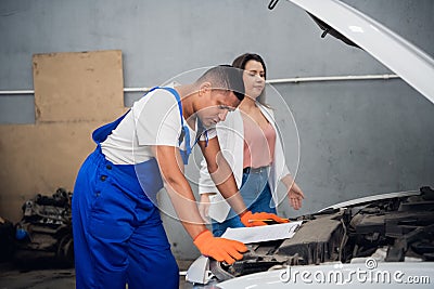 Customer and mechanic inspect broken car engine Stock Photo