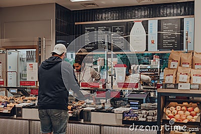 Customer ordering food from a counter inside Pret a Manger, separated from barista by protective plastic screen, London, UK Editorial Stock Photo