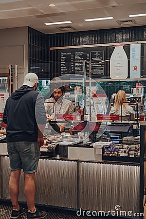 Customer ordering food from a counter inside Pret a Manger, separated from barista by protective plastic screen, London, UK Editorial Stock Photo