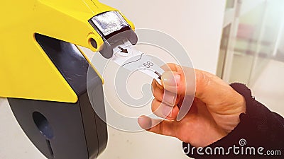 Customer pulls with hand a numbered ticket out of yellow number dispenser machine, to wait in service line and to be served when h Stock Photo