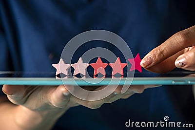 Customer satisfaction survey, give 5 star rating for review, positive feedback good experience, woman holding five star on tablet Stock Photo