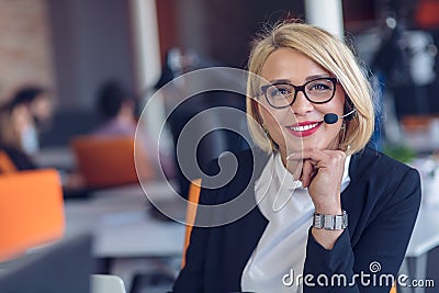 Customer service representative at work. Beautiful young woman in headset working at the computer Stock Photo