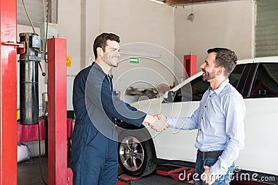 Customer Shaking Hands With Car Mechanic At Repair Shop Stock Photo