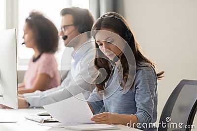 Customer support phone operator sitting at workplace holds read document Stock Photo