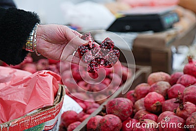 A customer taking red pomegranate split into pieces Stock Photo