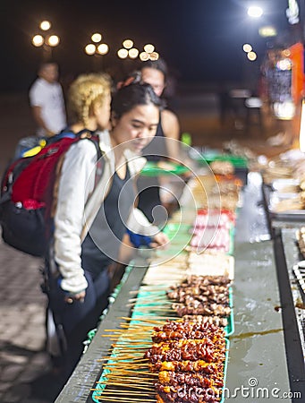 Customers choose from trays of barbecue food for sale,at night,along Rizal Boulevard Editorial Stock Photo