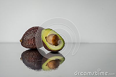 Cut avocado with bone, close-up on mirror background Stock Photo