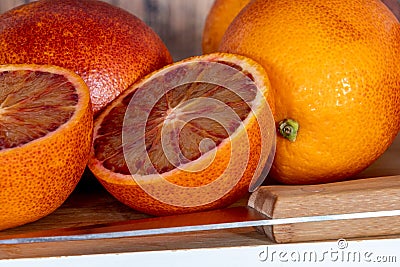 Cut blood oranges isolated on a wooden board with a knife Stock Photo