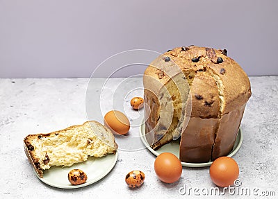 Cut Easter Panettone Italian Cake On Table With Colored Easter Hen, Quail Eggs. Fruitcake Stock Photo