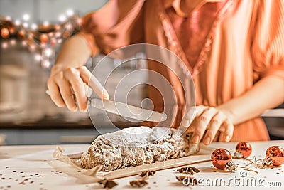 German culinary tradition on Christmas Eve. cut festive traditional German Stollen pie into pieces. girl in festive dress cuts Stock Photo