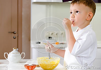 Cut little chef tasting his batter mixture Stock Photo