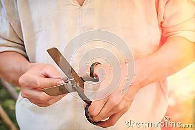 Cut metal scissors to making coins. Cutting silver to make money. Old scissors in big men's hands Stock Photo