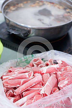 The cut mutton roll and the hot pot on the induction cooker Stock Photo