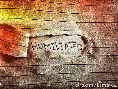 On a cut notebook page the word humiliated written Stock Photo