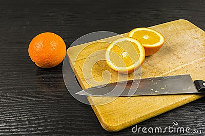 The orange is cut in half on a chopping board. Stock Photo