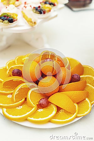 Cut orange and tangerine fruit on white plate Stock Photo