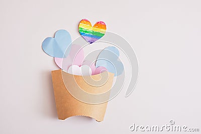 cut out colored paper hearts in packaging for fries on a gray background, transexual colors, lgbt pride concept Stock Photo