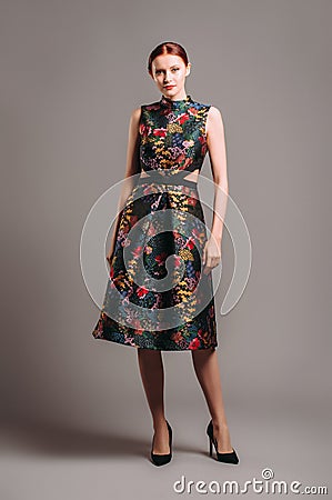 Cut out waist midi dress in floral embroidery with black high heels. Ginger lady posing in studio Stock Photo