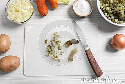 Cut pickled cucumbers near ingredients on white wooden table, flat lay. Cooking vinaigrette salad Stock Photo