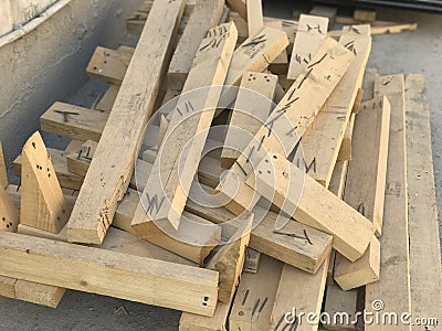 Cut pieces of wood used for shuttering and stacked at site used nails which are near miss Stock Photo
