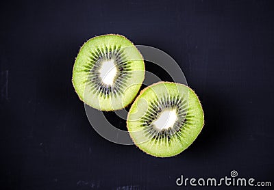 Cut, sliced fresh Kiwi fruit isolated, overlay on acrylic black scratchy grunge painting on canvas background. Overhead, top view Stock Photo