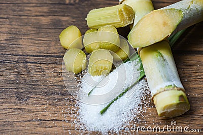 Cut sugar cane piece and white sugar wooden background top view Stock Photo