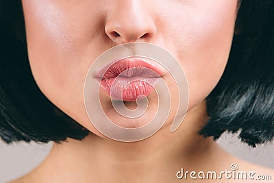 Cut view of beautiful lips with lipstick on. Young brunette with bob haircut. Kiss. Naked neck. Isolated on light studio Stock Photo