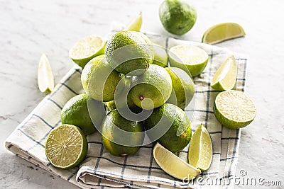 Cut and whole limes on a kitchen towel and a marble surface Stock Photo