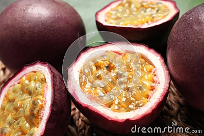 Cut and whole passion fruits maracuyas on wicker mat, closeup Stock Photo